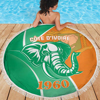 Round beach blanket on wooden deck by pool, green and orange elephant print with fringe