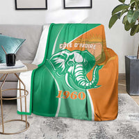 Cote d'Ivoire independence day blanket with elephant and 1960 design, green and orange, laid on rug