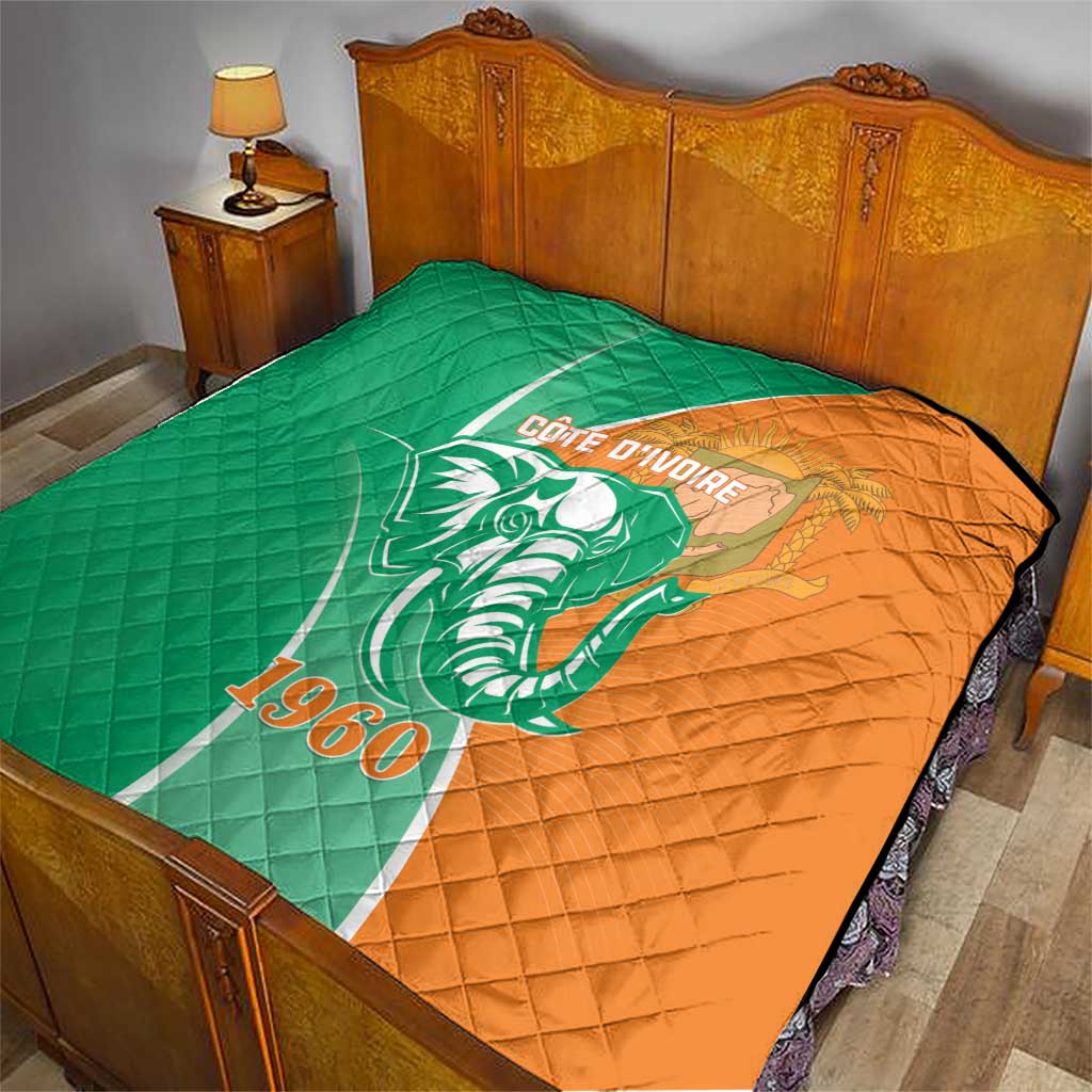 Green and orange quilt on bed with elephant emblem, Cote d'Ivoire text and 1960