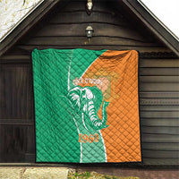 Green and orange quilt with elephant emblem, Cote d'Ivoire text and 1960, on wall