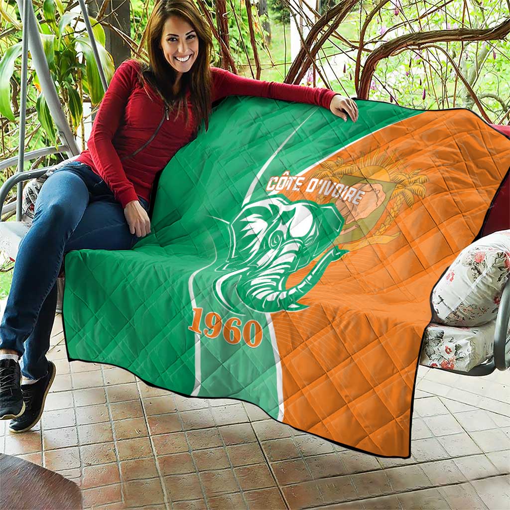 Green and orange quilt with elephant graphic, Cote d'Ivoire text and 1960, outdoors