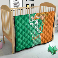 Green and orange quilt on wooden crib with elephant emblem and 1960