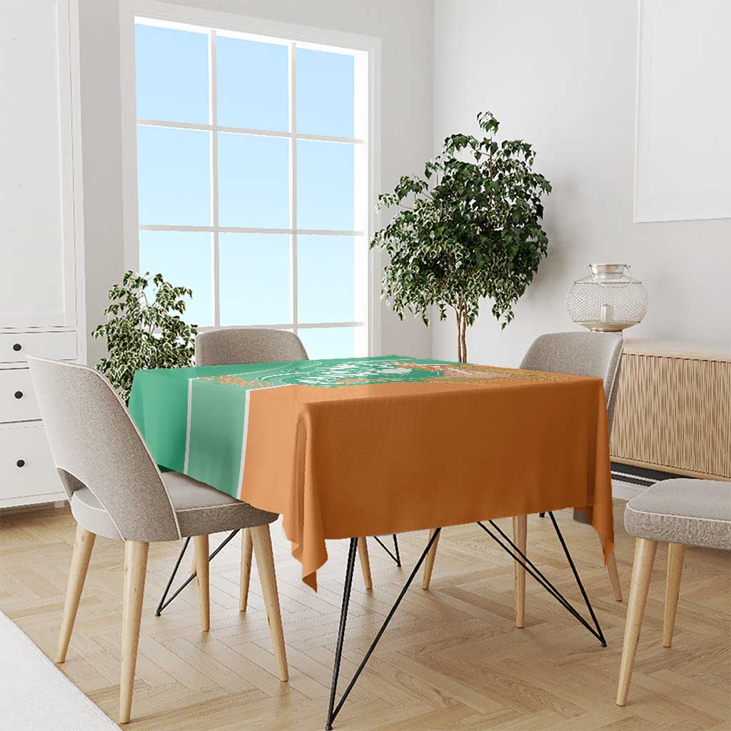 Two-tone green and orange tablecloth on dining table with draped edges and chairs