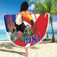 Round beach blanket spread out with Belize flag design, toucan artwork and fringe