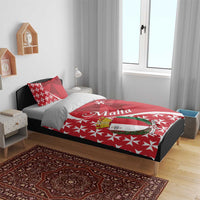 Red bedding set with Malta crest and Maltese cross star pattern on a bed with two pillows