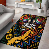 Black area rug with South African Heritage Day text, springbok, and colorful geometric design