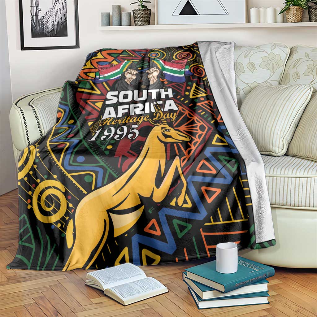 Black blanket draped with springbok and Heritage Day 1995 text on colorful African pattern.