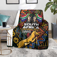Black blanket on armchair with multicolor springbok emblem and Heritage Day 1995 lettering.