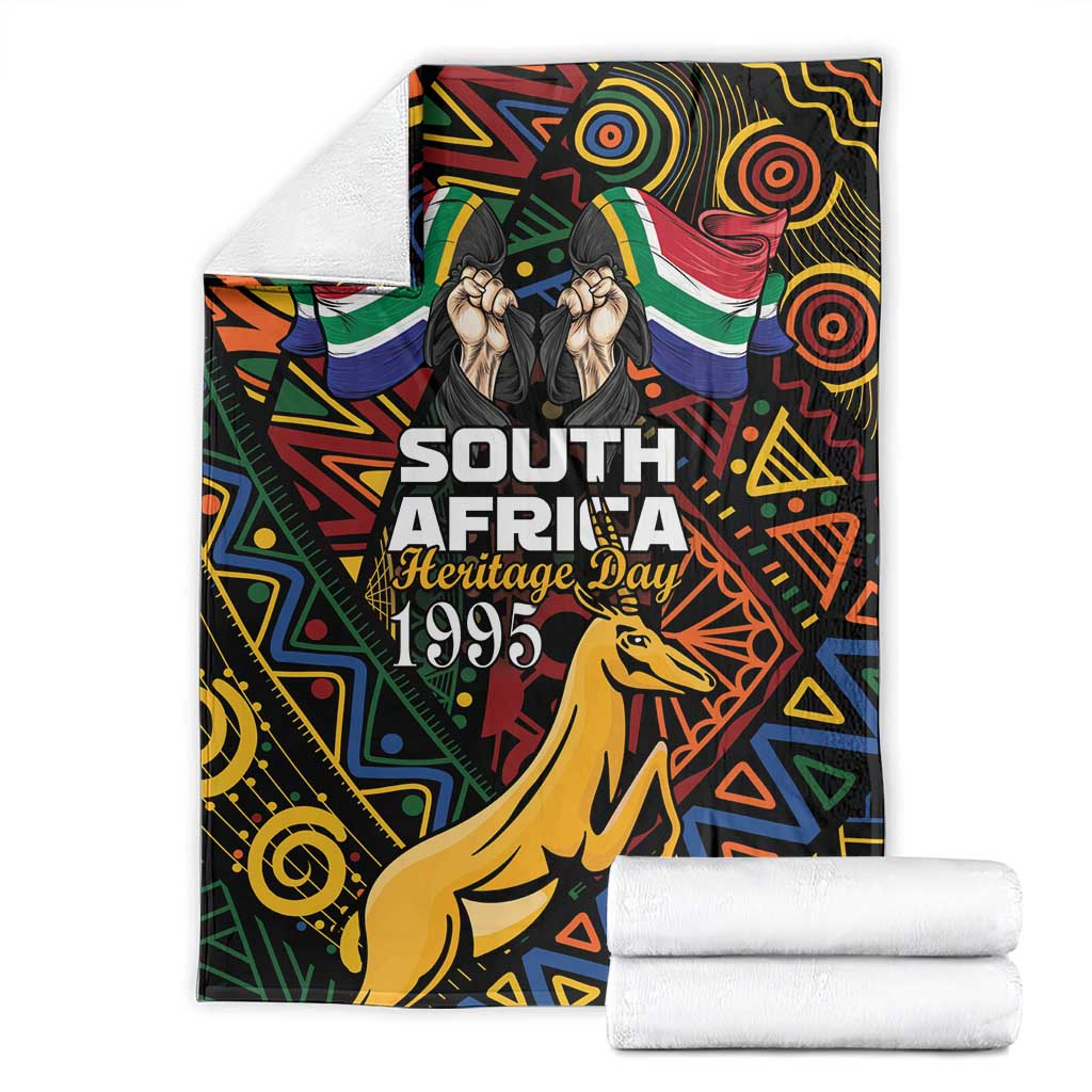 Black blanket with folded look; springbok, multicolor pattern, and Heritage Day 1995 text.