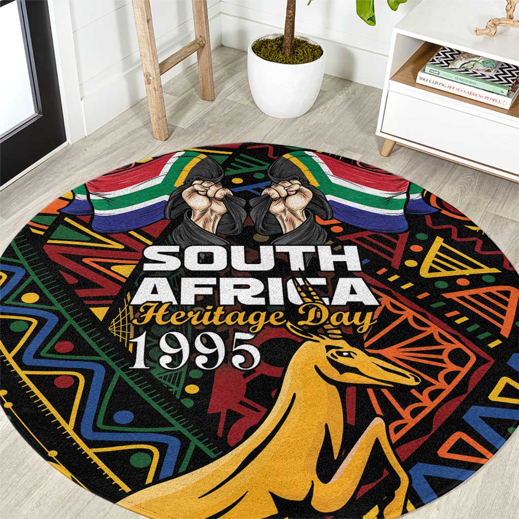 Black round carpet with 'South Africa Heritage Day 1995' and springbok illustration
