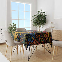 Black tablecloth with vivid African geometric pattern, set on dining table with chairs