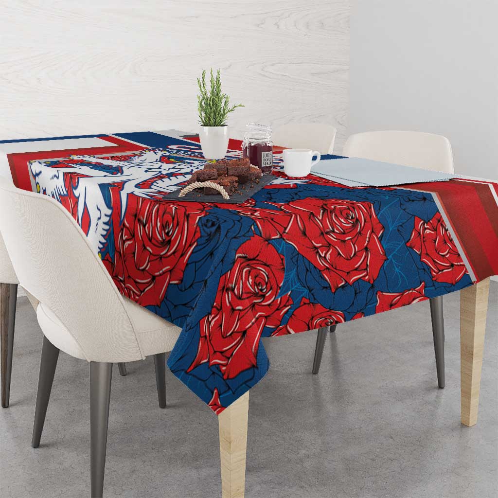 Red and blue tablecloth with lion and rose motif, draped over table corners.
