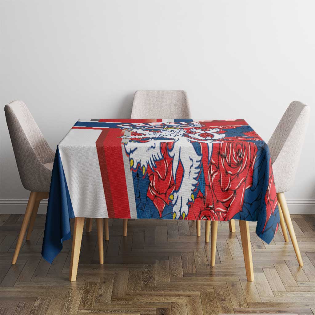 Red and blue rectangular tablecloth with lion and rose pattern, hanging over edges.