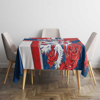 Red and blue rectangular tablecloth with lion and rose pattern, hanging over edges.