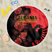 Round red beach blanket with black floral print, eagle emblem, and white fringed edge