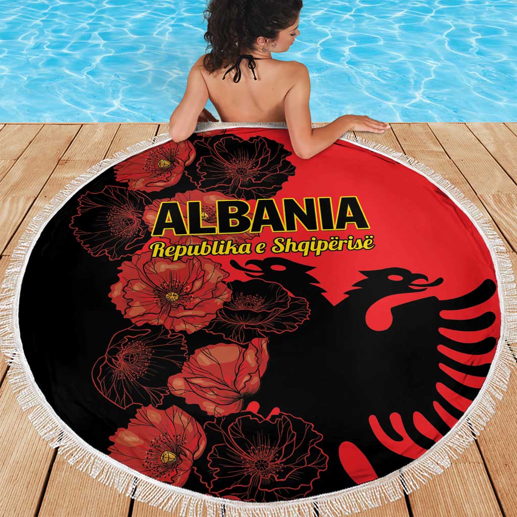 Round beach blanket with red-and-black floral design, Albania emblem, and white fringe