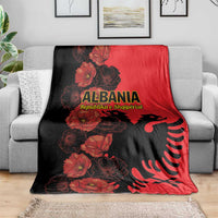Red and black Albania throw blanket with floral eagle design, shown on sofa