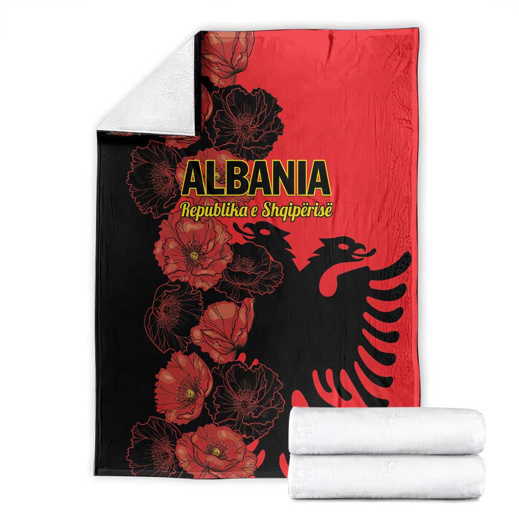 Folded red and black Albania throw blanket with floral eagle print, with folded towels