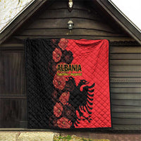 Quilt blanket hanging on wall, black and red halves with Albania crest and floral design.