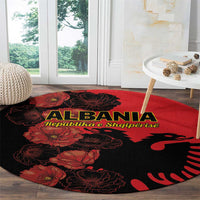 Round Albania carpet with red flowers and black eagle silhouette near sofa