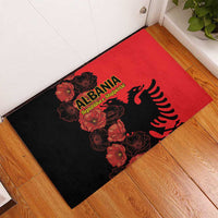 Red and black rubber doormat with Albania eagle and poppy flowers, corner view