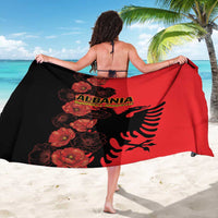 Red and black sarong with floral eagle graphic, held wide by arms
