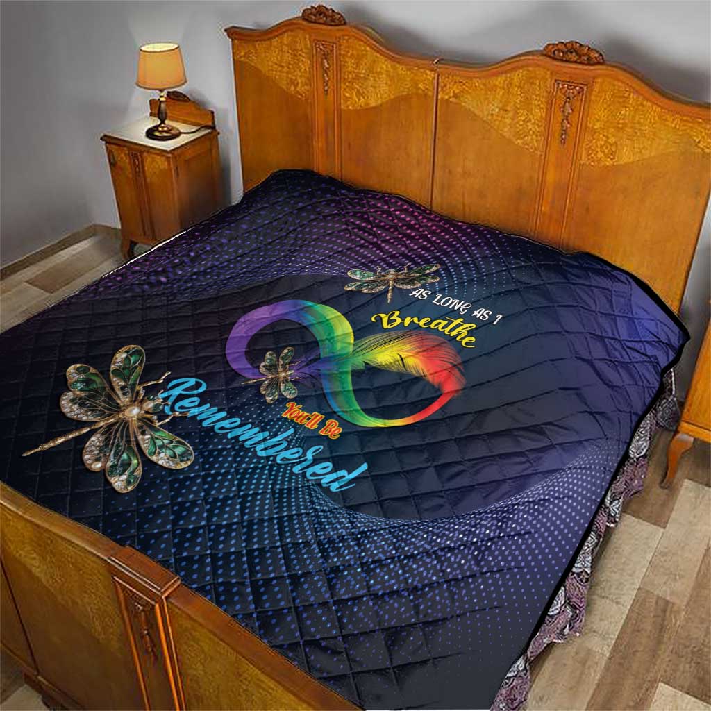 Navy quilt on a bed with diamond pattern, rainbow heart design and dragonfly applique