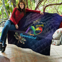 Navy quilt draped on a couch with rainbow heart center and dragonfly applique details