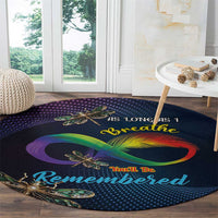 Round memorial carpet with dark navy base, rainbow infinity loop and dragonfly motifs near edge.