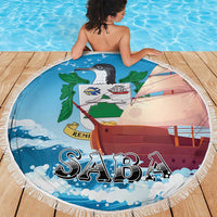 Blue round Saba beach blanket showing sailboat, waves, and leaf graphic; fringed edge.