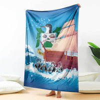 Blue SABA blanket with sailboat illustration, held up like a throw