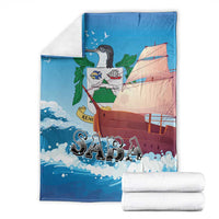 Blue sailboat blanket with “SABA” text, folded with white towels beside it