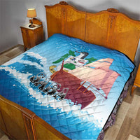 Blue quilt blanket on a bed with sailboat design, waves, bird, and “SABA” print