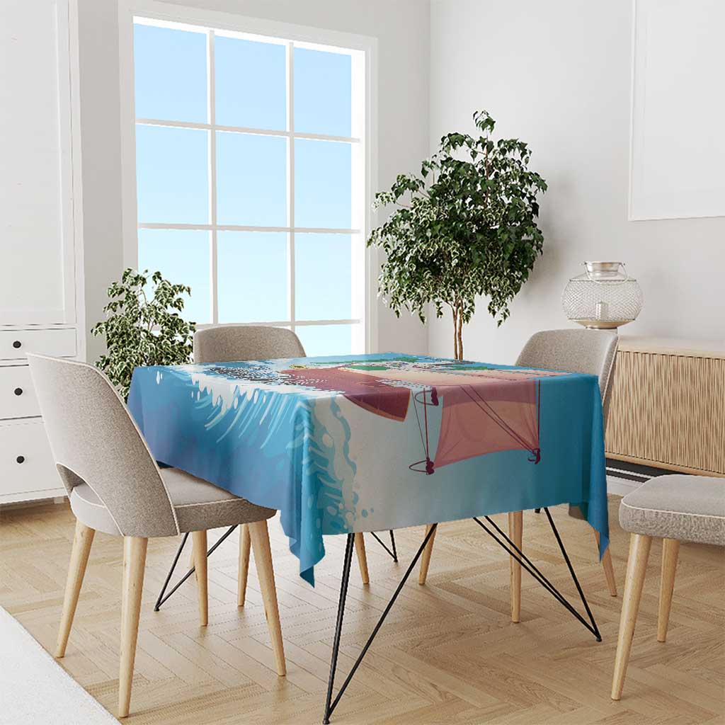 Blue sailboat tablecloth draped over a dining table, beach and sailboat artwork