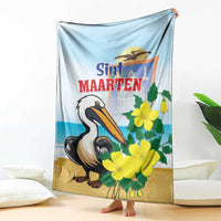 Light blue blanket featuring pelican, yellow flowers, and Sint Maarten graphic text