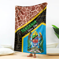 Blue-and-brown giraffe-pattern blanket with Tanzania-style text and emblem, draped