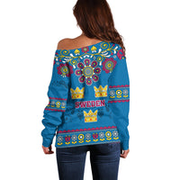 Back view: blue off-shoulder sweater with Sweden text, crown icons, and floral pattern border