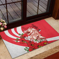 Red rubber doormat featuring merlion, white rays, and red flowers near doorway