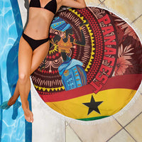 Round beach blanket with fringed border, blue-dressed woman on red-yellow-black print.