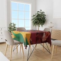 Red tablecloth with tropical Ghana design, green and yellow panels, on a long dining table.