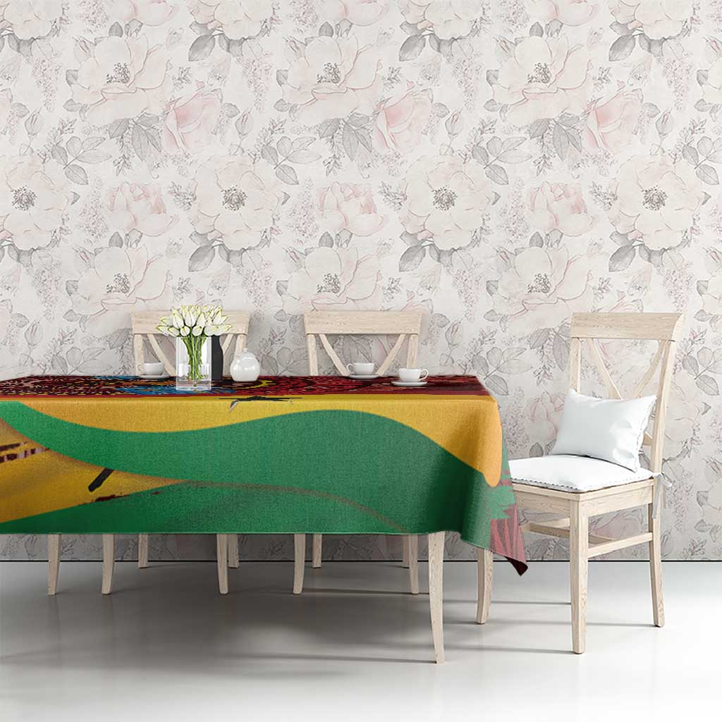 Red tablecloth with tropical motif, green and yellow curved bands, on dining table with chairs.