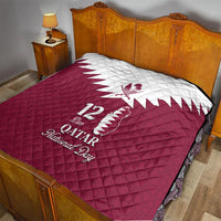 Red quilt on bed with white Qatar emblem, “12 Qatar,” and “National Day” text