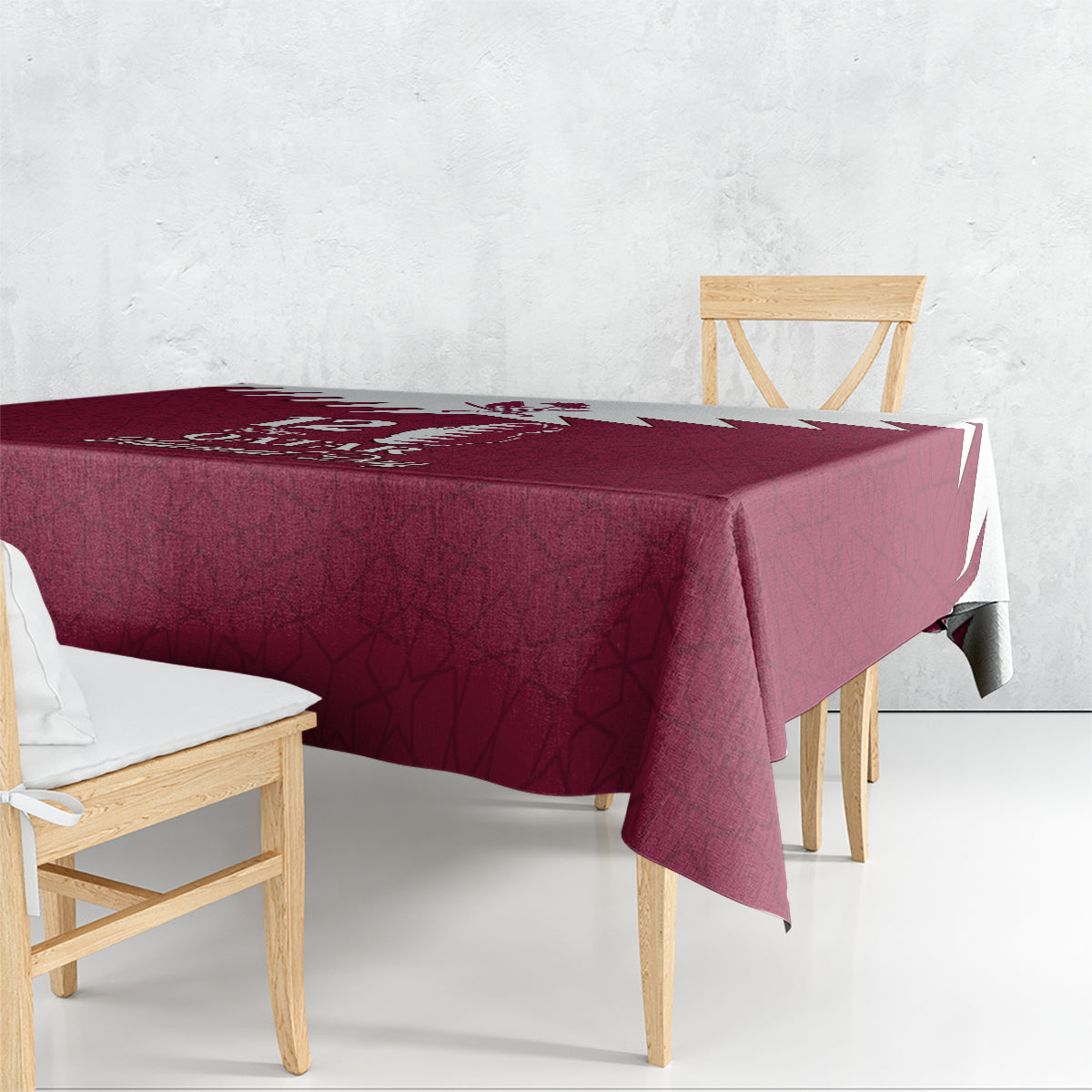 Red tablecloth draped on dining table, featuring Qatar map and Islamic geometric design.