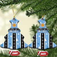 Blue bell-shaped Argentina Feliz Navidad ornaments hanging on a tree, striped with gold sun.