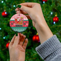 Red and green circular Hungary ceramic Christmas ornament being held on a hand with gold loop.