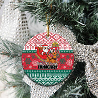 Red and green circular Hungary ceramic Christmas ornament hanging on a tree branch.