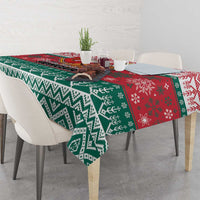 Close-up Christmas tablecloth with green zigzag pattern and red festive motifs across the edge.