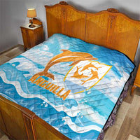 Blue quilt blanket on bed with orange Anguilla dolphin emblem and white wavy water print