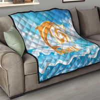 Blue quilt blanket on sofa with orange Anguilla dolphin logo and white wavy water pattern