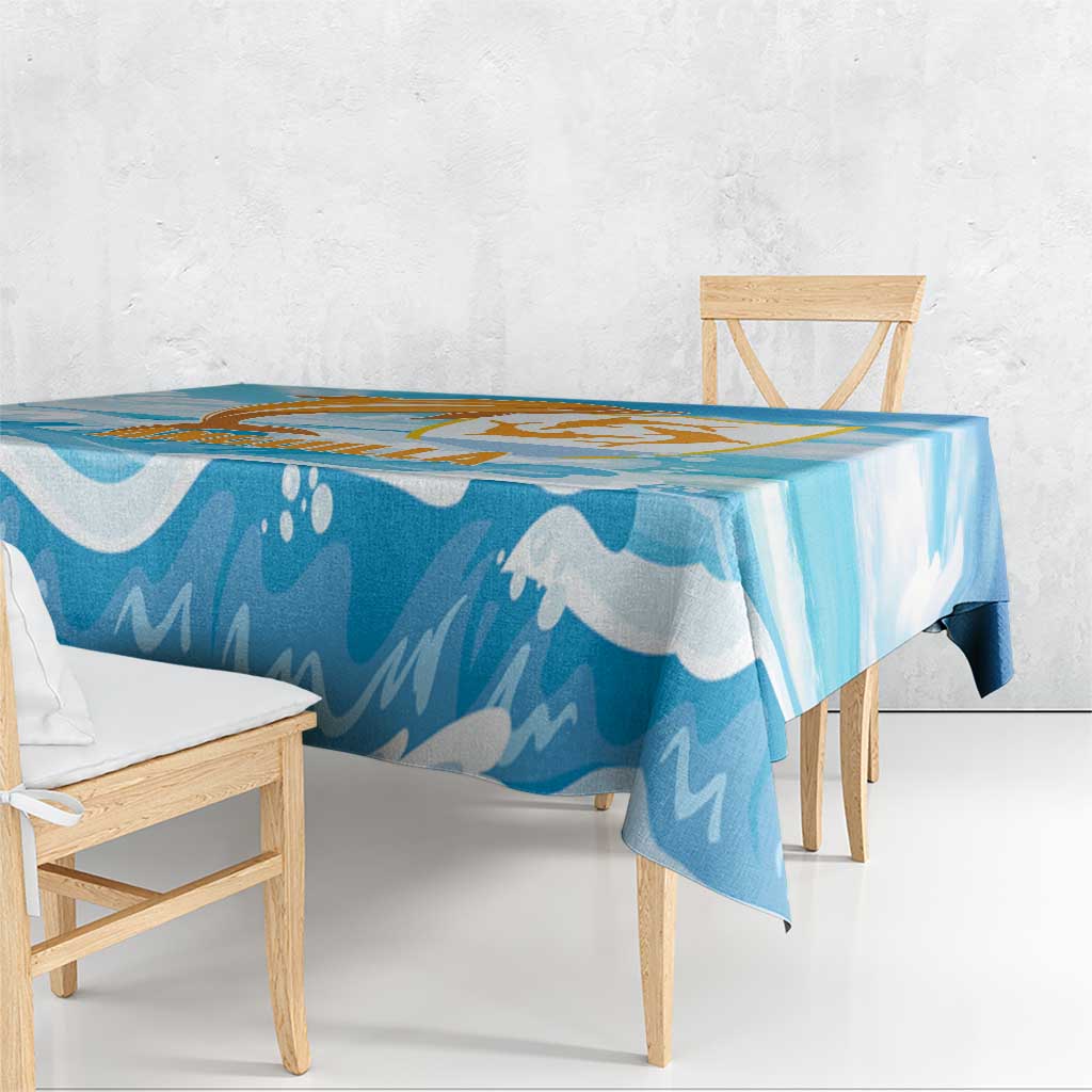 Blue tablecloth with orange and gold dolphin design and wave motifs on tabletop.